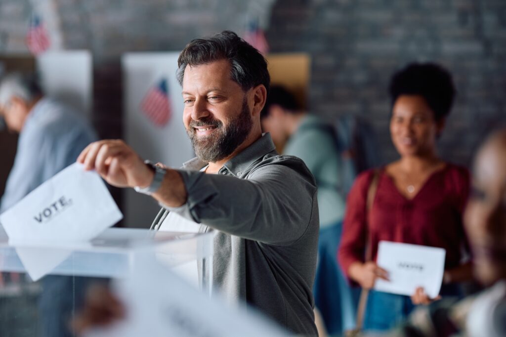 Happy man voting for the elections in United States of America and looking at camera.