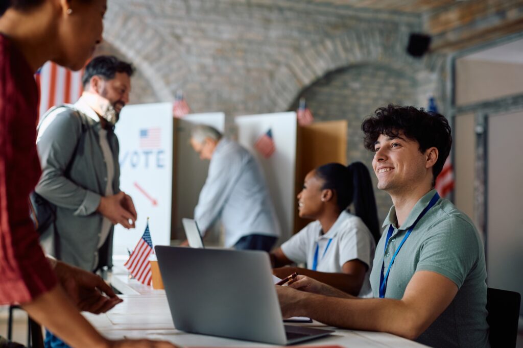 Happy volunteer assisting voters during elections at polling station.